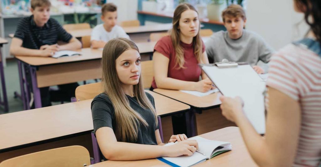 Skoleklasse der kigger på læreren mens de modtager sexualundervisning